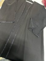 ⁦عباية راقية تتميز بشريط تطريز  خرز رفيع ممتد على طول العباية من الأمام وعلى أطراف الأكمام ليعطي لمسة من الفخامة الهادئة.⁩ - الصورة ⁦3⁩